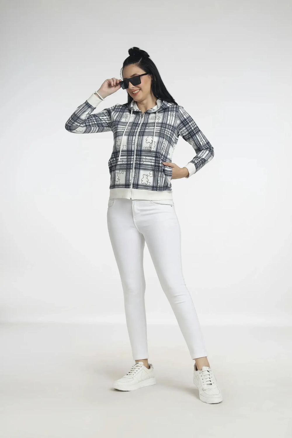 Woman wearing a plaid shirt, white pants, and sneakers on a white background