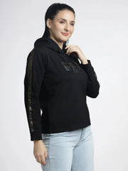 Woman wearing a black hoodie with gold accents on a white background
