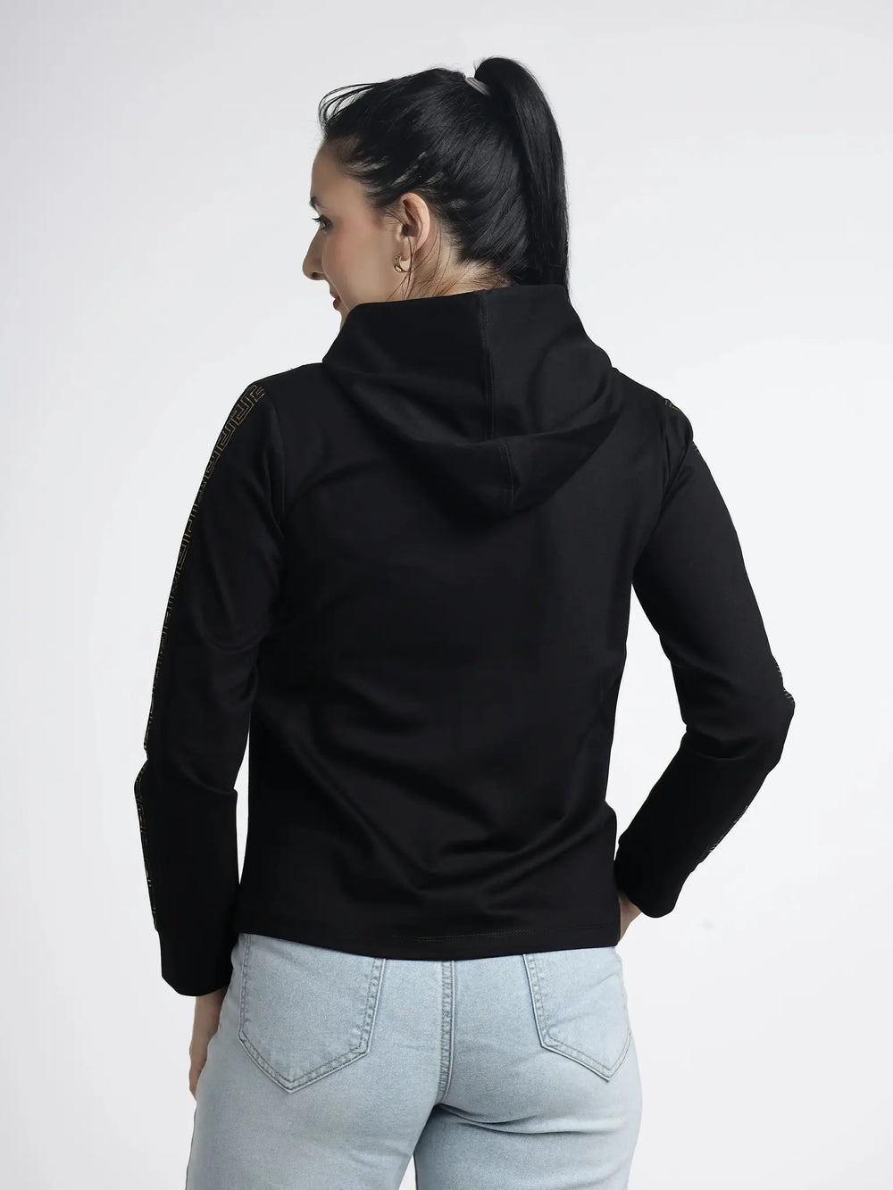 Person wearing a black hoodie and light blue jeans on a white background