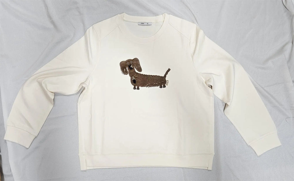 White long-sleeve shirt with a brown dachshund design on a light gray background