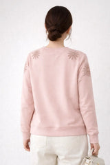 Person wearing a pink sweatshirt with floral patterns on a white background