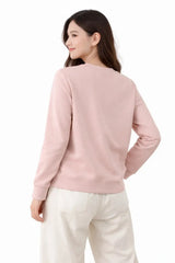 Woman wearing a pink sweater and white pants on a white background
