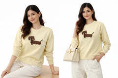 Two images of a woman wearing a light yellow sweater with a dachshund design, one sitting and one standing.