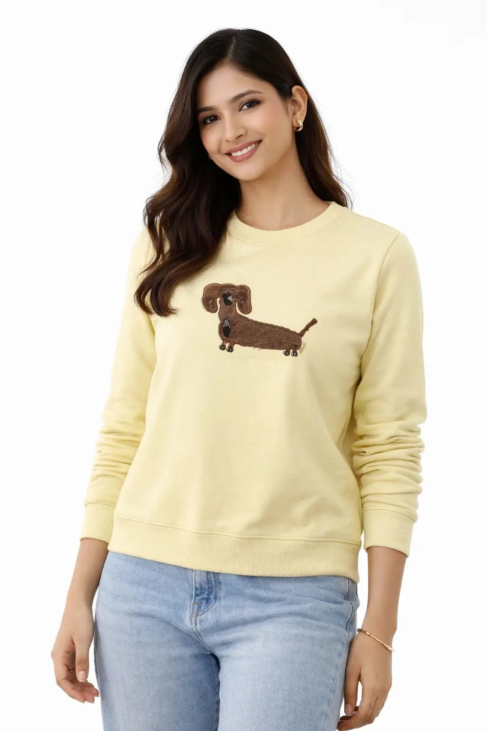 Woman wearing a light yellow sweatshirt with a dachshund design on a white background
