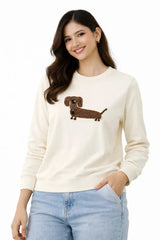 Woman wearing a cream sweater with a dachshund design on a white background