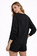 Woman wearing a black sweatshirt and shorts set on a white background