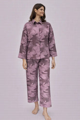 Woman wearing a purple camouflage pajama set on a light gray background