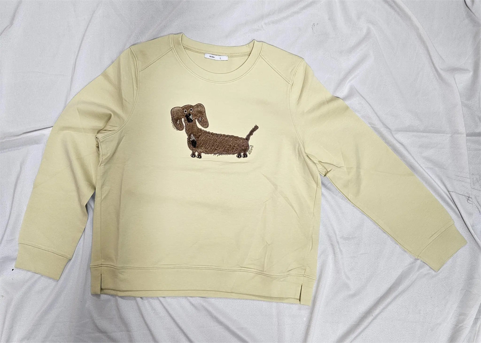 Beige sweatshirt with a dachshund graphic on a white background