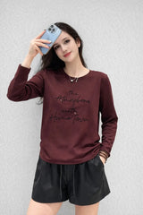 Woman wearing a burgundy sweatshirt with text and black shorts against a light gray background
