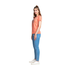 Woman wearing a coral t-shirt and blue jeans on a white background