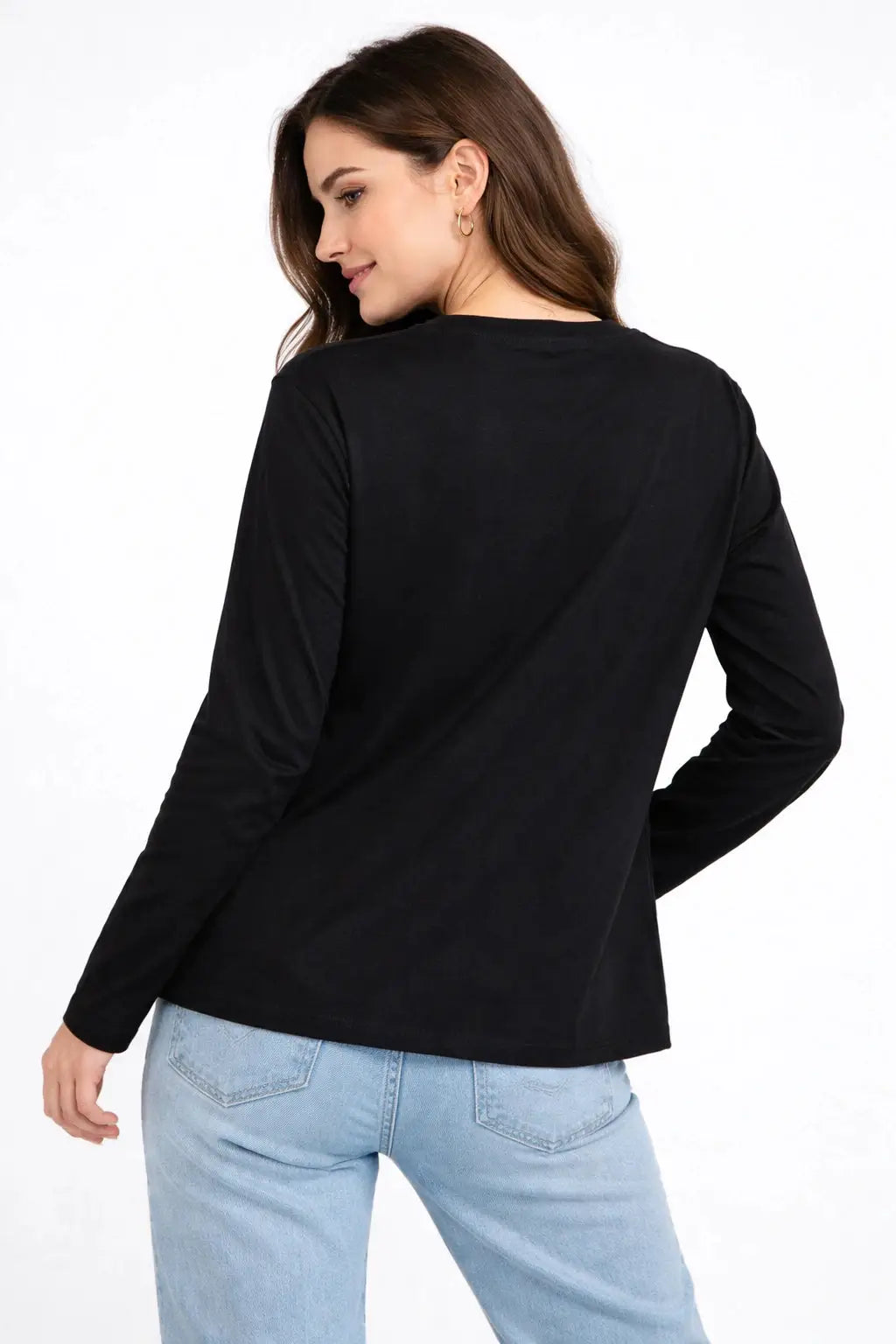 Woman wearing a black long-sleeve top and light blue jeans on a white background