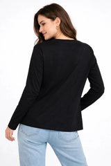 Woman wearing a black long-sleeve top and light blue jeans on a white background