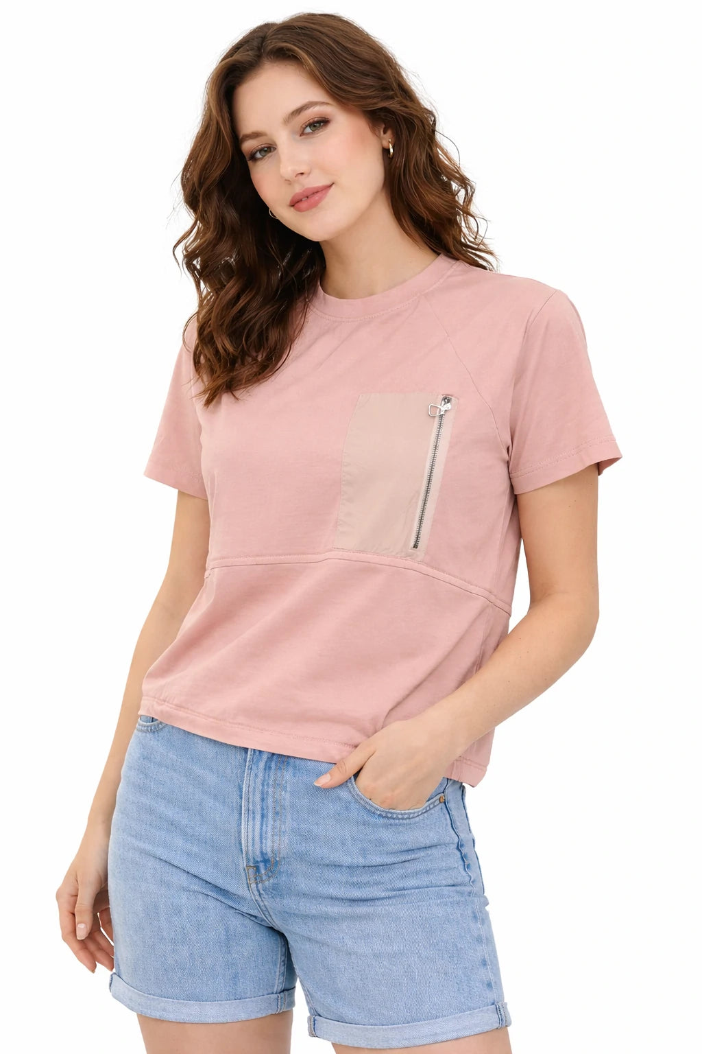 Woman wearing a pink t-shirt with a zipper pocket and denim shorts on a white background