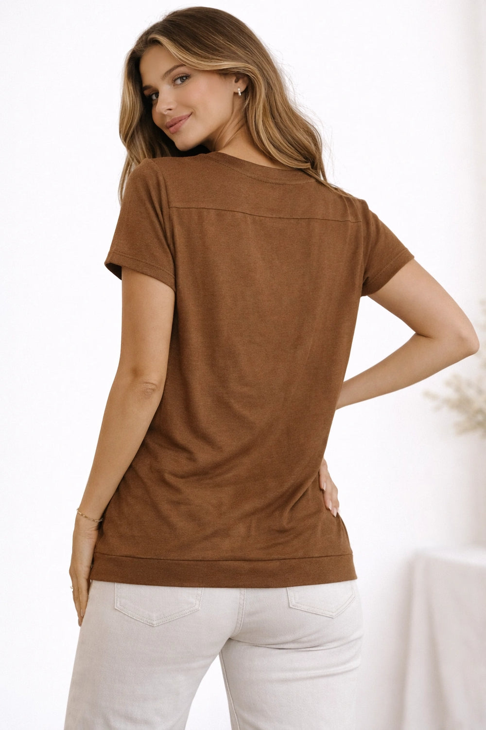 Woman wearing a brown t-shirt and white pants on a white background