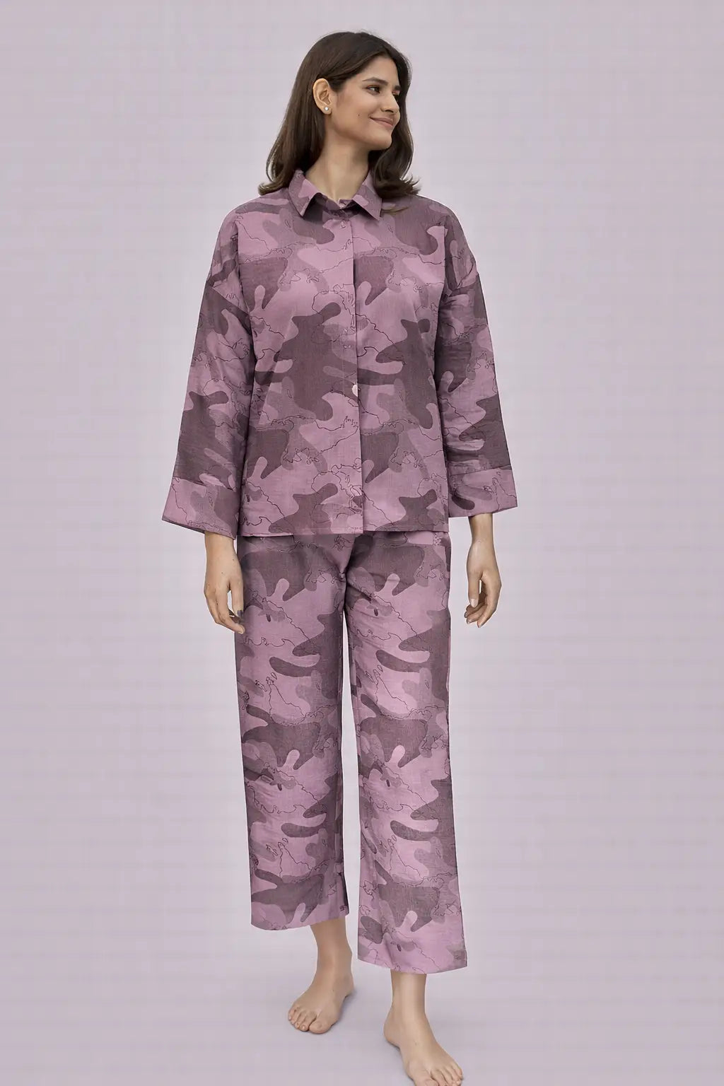 Woman wearing a purple camouflage pajama set on a light gray background